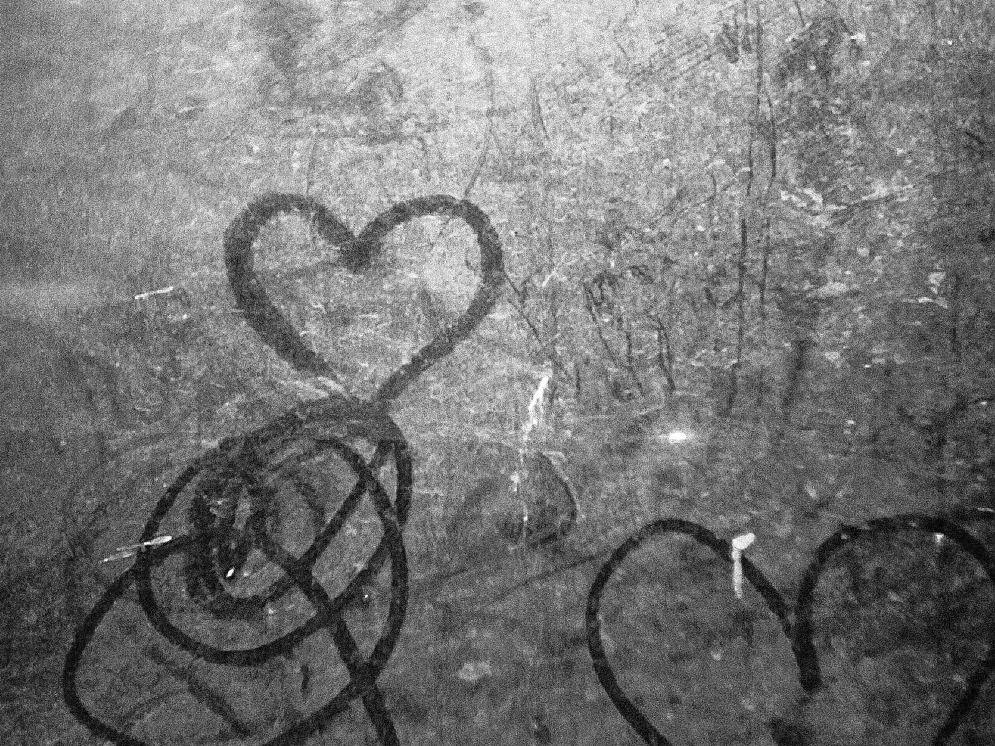 Hearts drawn on a weathered, textured surface with abstract shapes and lines around them.